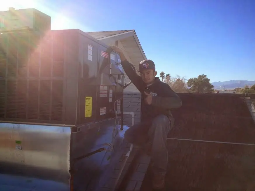 HVAC technician performing AC Tune-Up on a rooftop unit in Turner